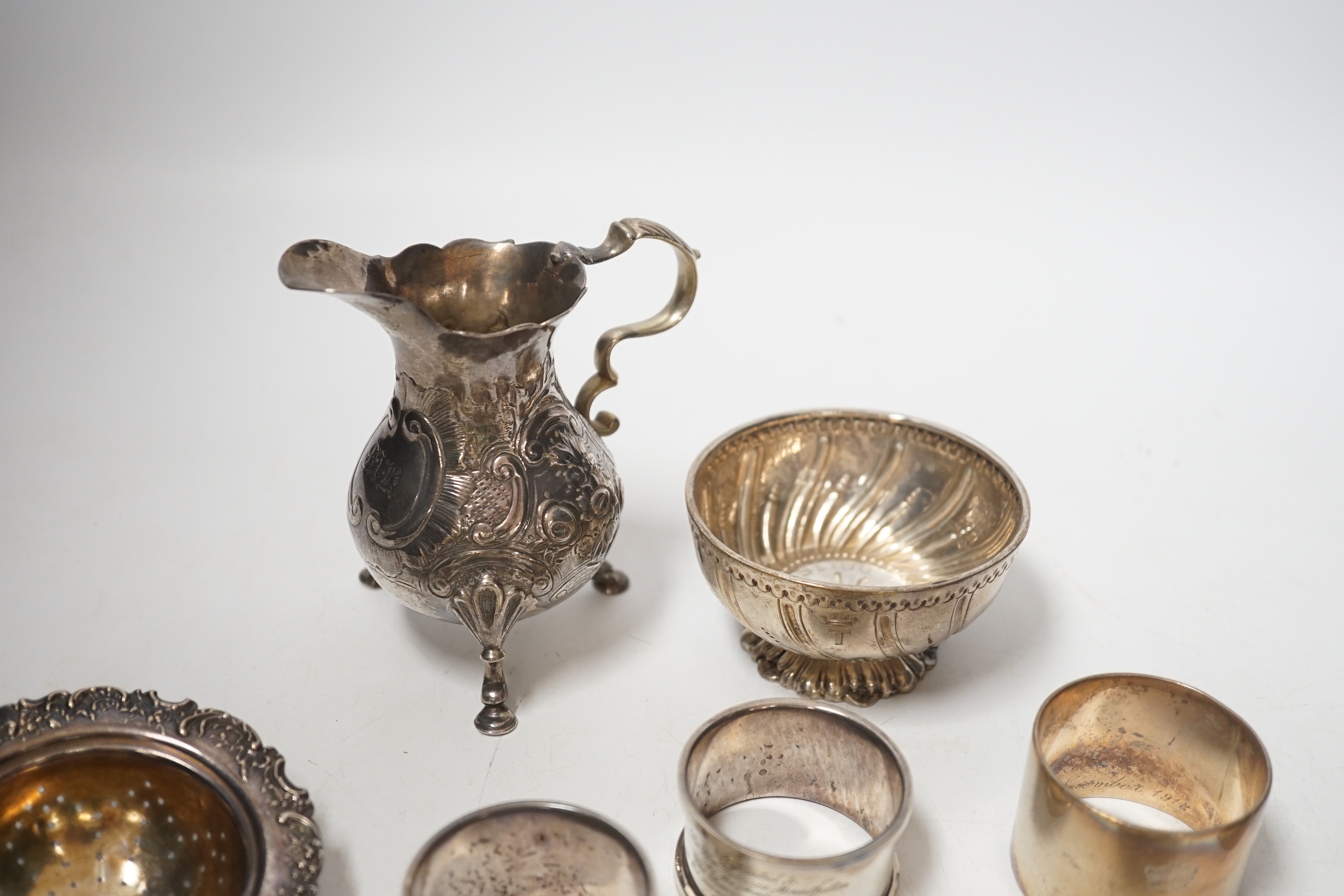 Sundry silver including six silver napkin rings, an 800 standard tea strainer and a white metal bowl and cream jug.